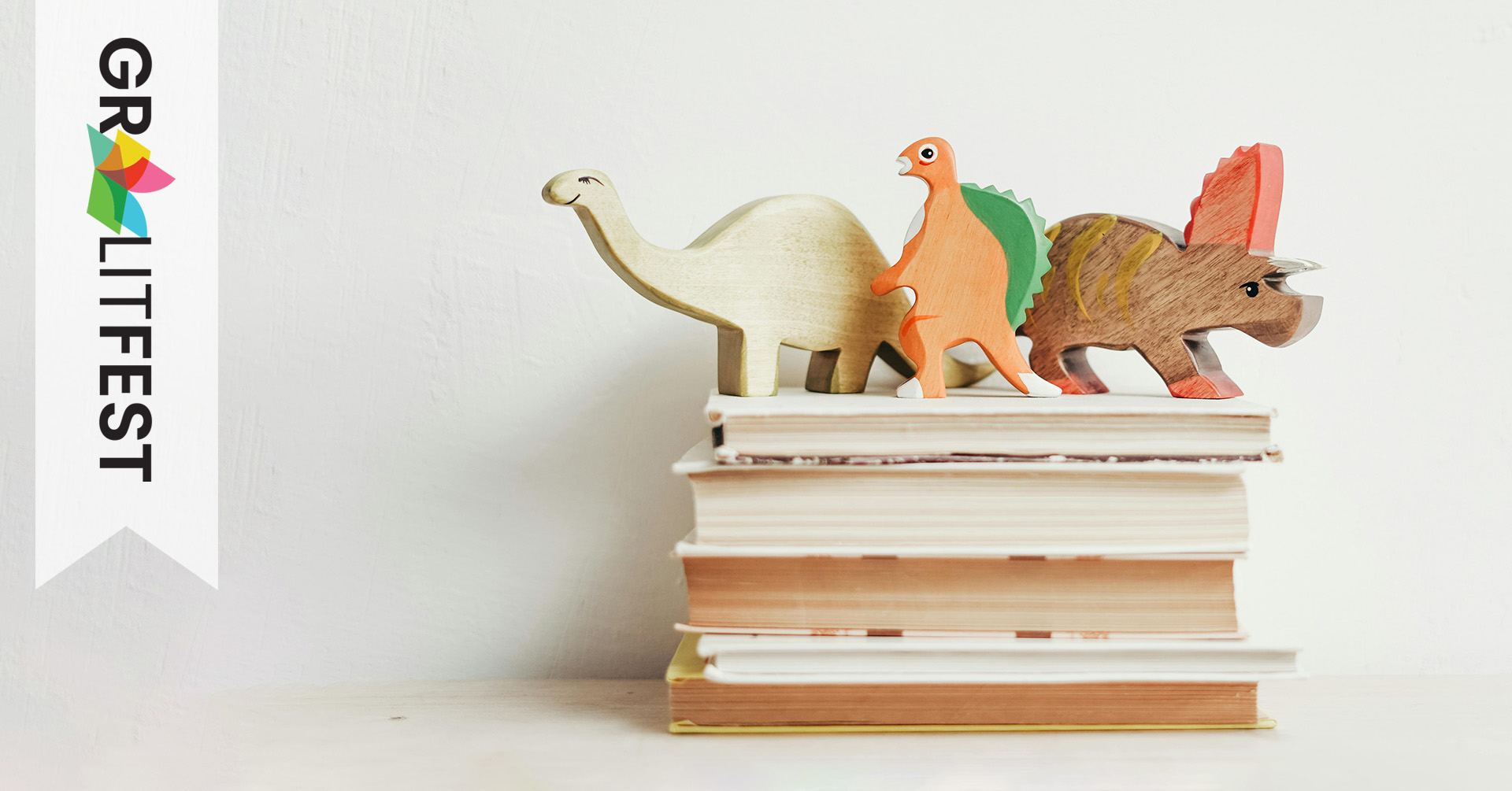 wooden dinos on stack of books