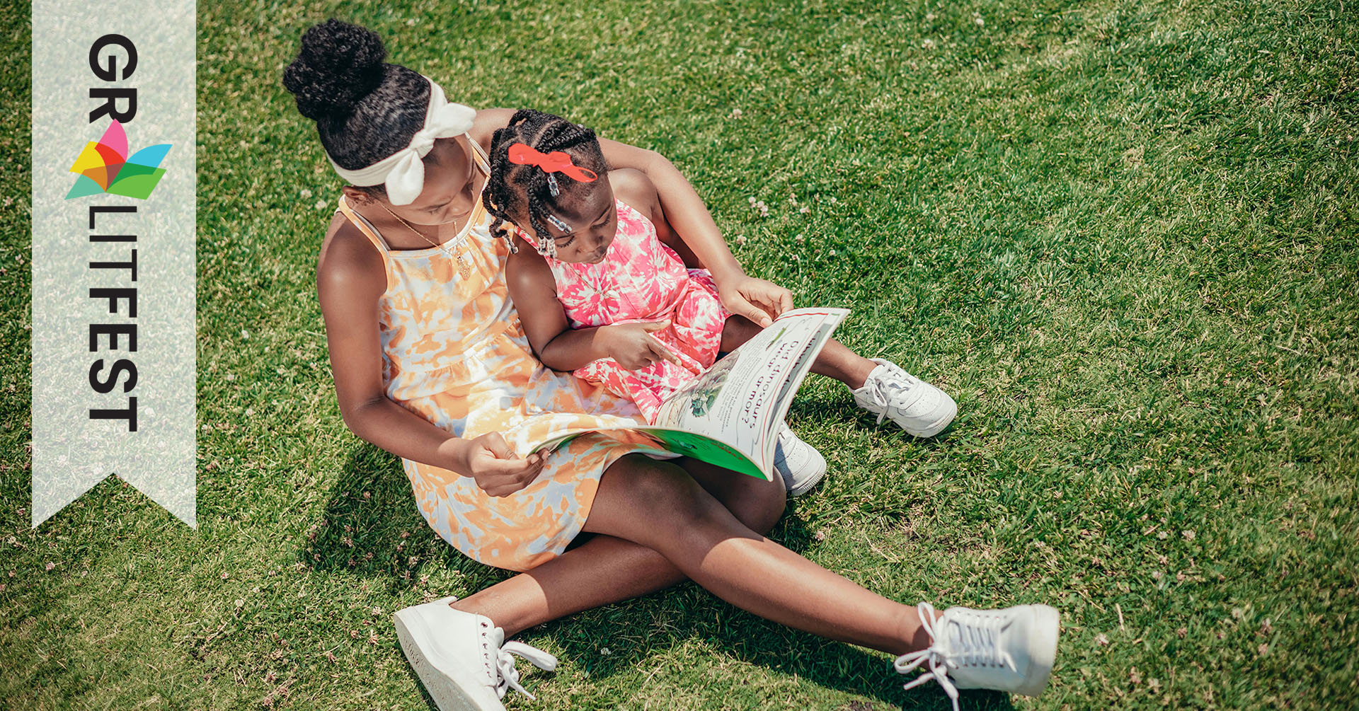 child reading to younger child on lawn